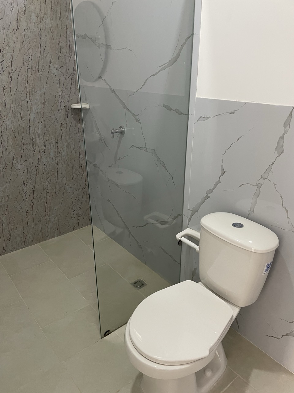 Baño en mármol con ducha y sanitario de la habitación triple